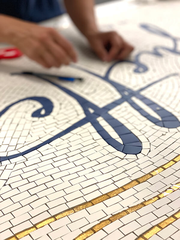 Mosaicist working on a floor tiles carpet